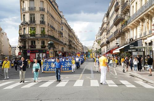 来自欧洲各国的上千名法轮功学员八月二十六日上在巴黎共和广场举办集会后游行，法国前教育部长霍斯塔利埃女士（中）走在队伍的最前列。